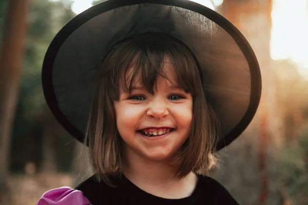 Lächelndes Mädchen verkleidet als Hexe im Wald zu Halloween — Stockfoto