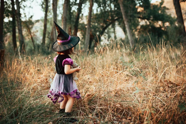 Fille debout déguisée en sorcière dans les bois pendant Halloween — Photo