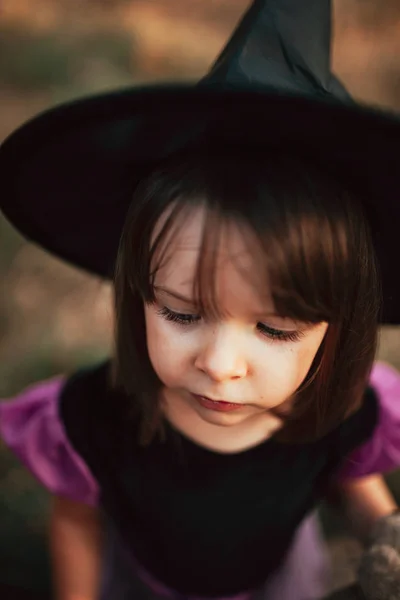 Улыбающаяся девушка, замаскированная под ведьму в лесу во время Хэллоуина — стоковое фото