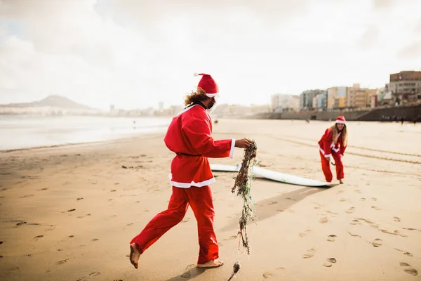To surfere utkledd som julenisse på stranda – stockfoto