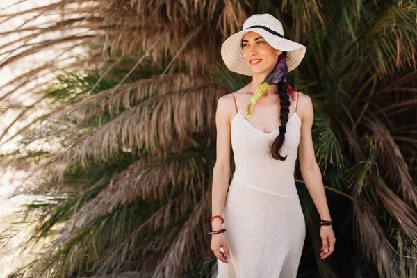 Usmívající se žena v šatech stojící blízko palmy — Stock fotografie
