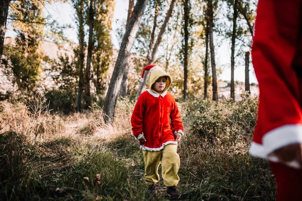 Gutt forkledd for julen i skogen med familien sin – stockfoto