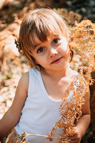 Pequena menina branca se agachando na floresta entre samambaias — Fotografia de Stock