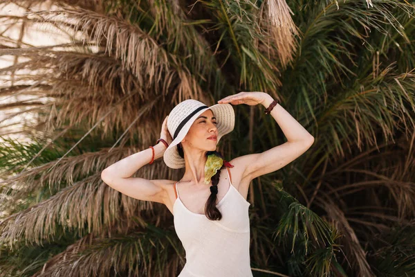 Mujer sonriente usando vestido de pie cerca de la palmera —  Fotos de Stock