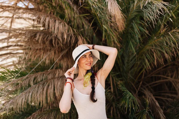 Uśmiechnięta kobieta ubrana w sukienkę stojąca blisko palmy — Zdjęcie stockowe