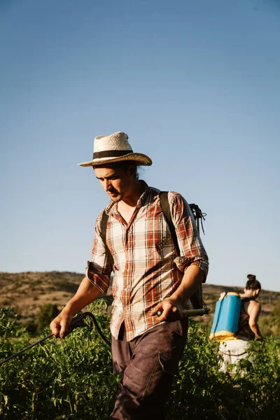 Młody rolnik spryskujący nawóz organiczny ręcznym zbiornikiem pompy — Zdjęcie stockowe