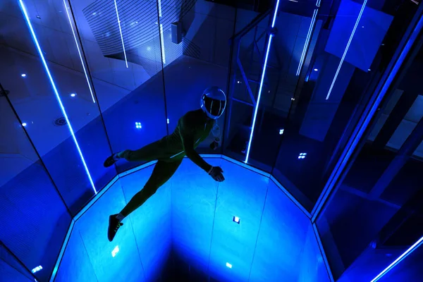 A man flier doing stunts in an indoor wind tunnel