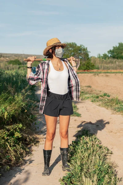 Hasır Şapkalı Genç Çiftçi Kadın Cerrahi Maske Çapayla Yürüyor — Stok fotoğraf