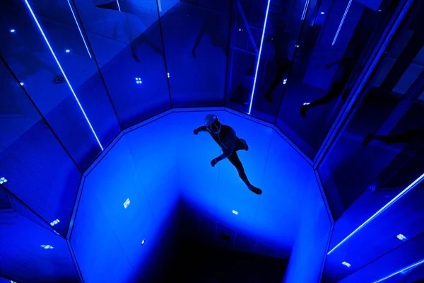 A man flier doing stunts in an indoor wind tunnel