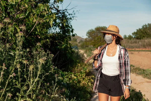 Hasır Şapkalı Genç Çiftçi Kadın Cerrahi Maske Çapayla Yürüyor — Stok fotoğraf