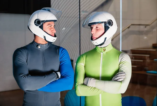 Two smiling flying men are prepared to fly in the wind tunnel.