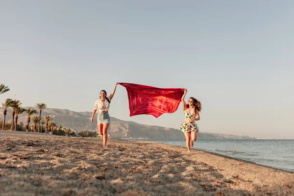 Dwie Kobiety Biegające Trzymające Szalik Fali Relaksują Się Szczęśliwe Plaży — Zdjęcie stockowe