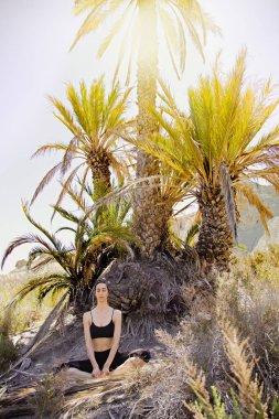 Güneşli bir günde çölde yoga yapan genç aktif bir kadın, sağlık ve aktif yaşam konsepti