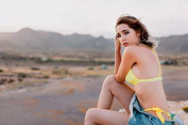 Kumsalda sarı mayo giyen bir kadın.