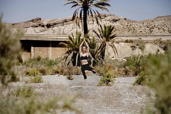 Joven mujer activa practicando yoga en el desierto en un día soleado, salud y concepto de vida activa — Foto de Stock