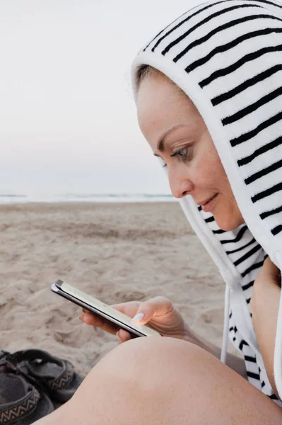 Femme utilisant son smartphone à la plage avec towell crochet — Photo