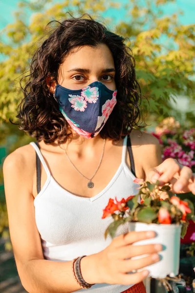 Frau mit Gesichtsmaske gärtnert im Gewächshaus covid-19 — Stockfoto