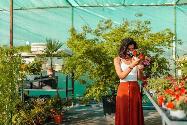 Mulher com máscara facial jardinagem em estufa covid-19 — Fotografia de Stock