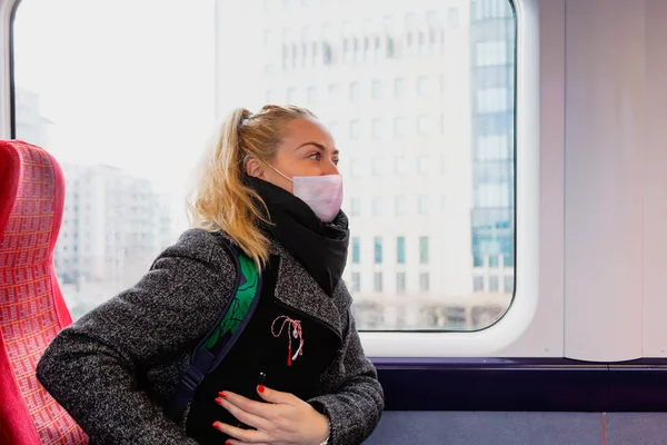 Žena s hygienickou obličejovou maskou udržuje bezpečnou vzdálenost v sedadlech vlaku kvůli koronaviru — Stock fotografie