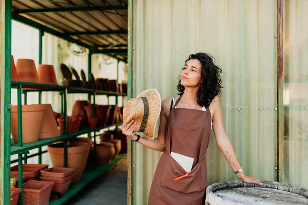 Mujer se abanica con su sombrero de paja en la puerta de su negocio de cerámica — Foto de Stock