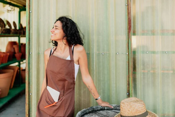 Ung kvinnlig säljare ler mot dörren till ett keramikföretag — Stockfoto