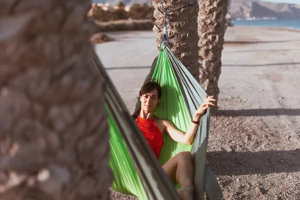 Mujer acostada en hamaca entre palmeras en la playa —  Fotos de Stock