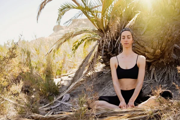 Young active woman practicing yoga in desert on sunny day, health and active life concept