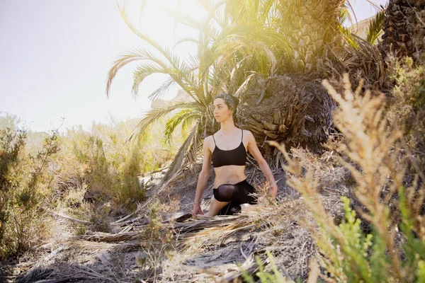 在阳光明媚的日子里，年轻活跃的女人在沙漠里练习瑜伽，健康和积极的人生观 — 图库照片