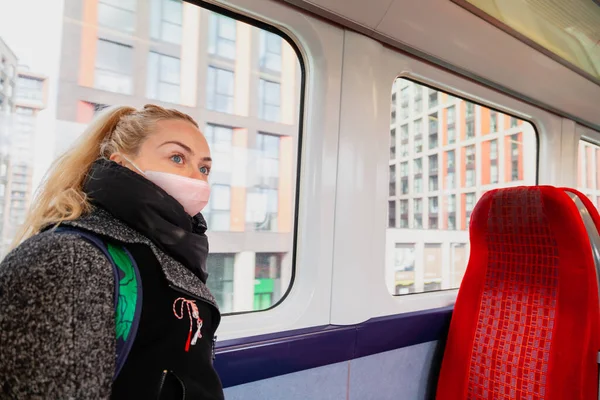 Žena s hygienickou obličejovou maskou udržuje bezpečnou vzdálenost v sedadlech vlaku kvůli koronaviru — Stock fotografie