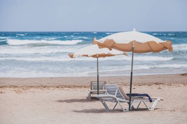 Güneş yatakları ve şemsiyeleri olan boş bir sahil.