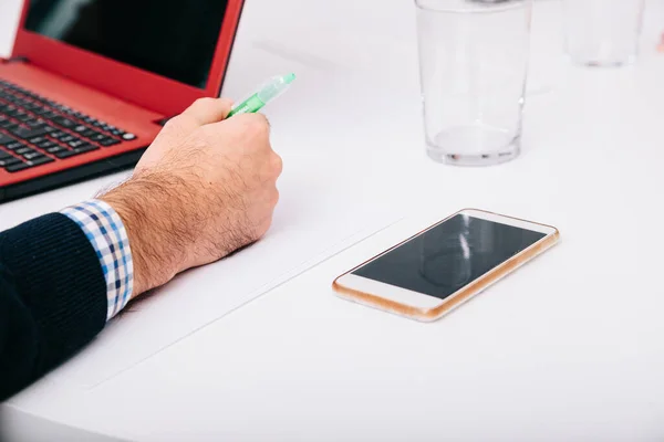 Fechar o smartphone e entregar a mesa com laptop no escritório — Fotografia de Stock