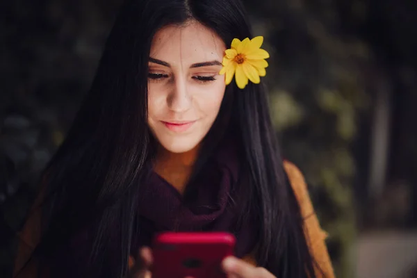 Femme utilisant son téléphone avec de la fleur dans ses cheveux — Photo