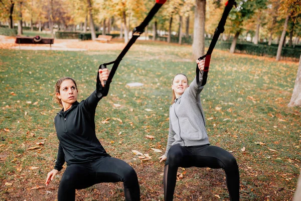 Les femmes s'entraînent avec trx à l'extérieur dans le parc. — Photo