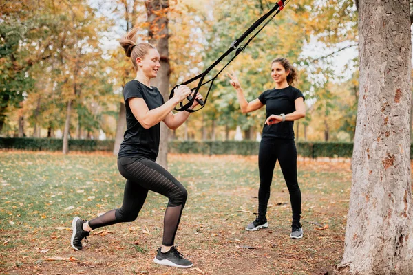 Kadınlar parkta trx ile antrenman yapıyor..
