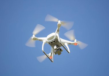 Beyaz dron yukarıdan filme dijital kamera ile. Hava gözetleme için uygun. Açık mavi gökyüzü arka plan.