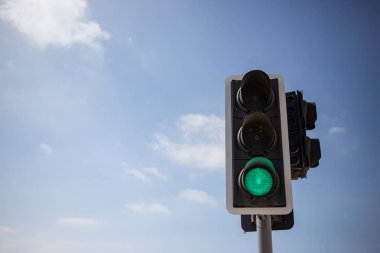 Yeşil trafik ışığı. Yolda gitmek güvenli sinyal. Mavi gökyüzü birkaç bulutlar arka plan ile. Görünümü, metin için yer altında yakın çekim.