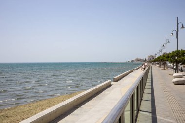 Kıbrıs, Larnaka şehir. Denizi çevresinde gezinti için taş yol. Liman, plaj, bina, mavi gökyüzü arka plan.