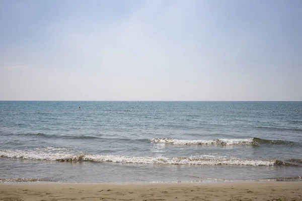Sandy plaj, deniz ile düşük dalgalar, mavi gökyüzü ile zemin için az bulutlu. Yaz hedef. Görünümü kapatın.