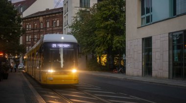 Toplu taşıma kavramı. Sarı elektrikli tramvay, Berlin, Almanya geceleri yayılıyor. Şehir ve insanlar arka plan.