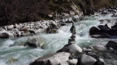 Ağır çekimde dengeli bir taş cairn Ala-Archa nehir kıyısında, akan dağ deresinin ortasında. Kaya ve vahşi arazi. Navigasyon, macera ve açık hava ruhu. Rafting, kano ve kano ortamı.
