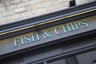 Dükkan önünde balık ve cips tabelası var.