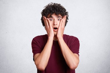 Yakışıklı hayrete erkek portresi tutan eller yanaklarda, şok edici haberler, ifade surprisement, izole beyaz beton duvara duymak düştü, çene suskun, varlık sürpriz. Duygular kavramı