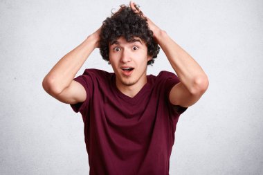 Hayret Kafkas genç erkek şok ifade ile yatay portre rahat kıyafetler giyer, beyaz beton zemin üzerine izole bir haber ile ilgili surprisement ifade eder. OMG kavramı