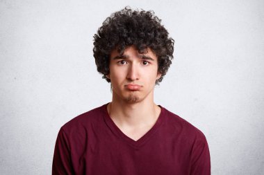 Üzgün üzgün ve hayal kırıklığına olmak olumsuz haberler ile memnun dudak, çekici erkek eğrileri alt headshot beyaz beton duvara teşkil etmektedir. Kasvetli genç bir şeyle şikayetçi