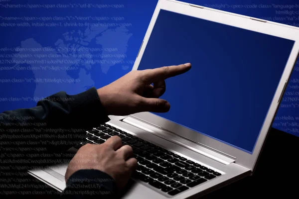 Unrecognizable hacker steals data information, works on laptop computer, points at screen, involved in computer crime, poses against dark blue background. Double exposure. Internet crime concept