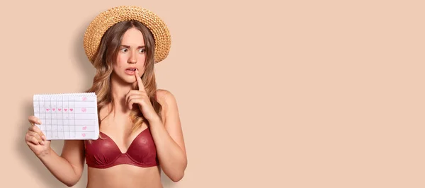 Indoor Shot Thoughtful Embarrassed Female Wears Summer Hat Swimsuit Holds — Stock Photo, Image