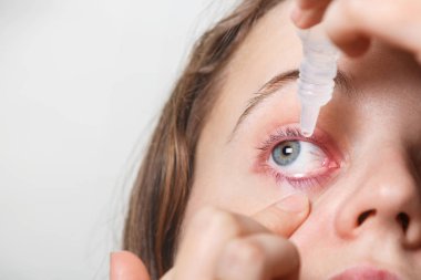 Erkek inflamated kırmızı gözüne damla koyar, conjuctivitis, üzerinde beyaz izole muzdarip. Kadın göz damlası geçerlidir. Göz tedavi ve sağlık kavramı