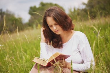 Çekici görünüm ile güzel güzel erkek portresi açık havada kitap okur, yeşil alana oturur, yazın güneşli hava ve harika doğa görünümü sahiptir. Okuma sırasında sakin atmosferi kadın seviyor