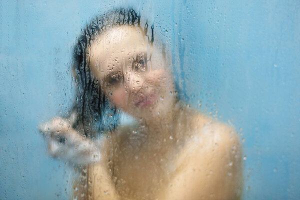 Чувственный портрет молодой худой женщины с обнаженным телом и мокрыми волосами, вымытый в придурке. Ослабленное изображение для фона. Очаровательная неузнаваемая женщина чувствует облегчение и свободу в ванной комнате
