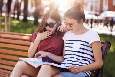 Neşeli genç kadın ile ifade kitapta, kayıtsızca, giyinmiş bilgi memnun parkta poz, yaz aylarında dinlenmek, dergiye odaklı bankta oturmak. İnsanlar ve yaşam tarzı kavramı